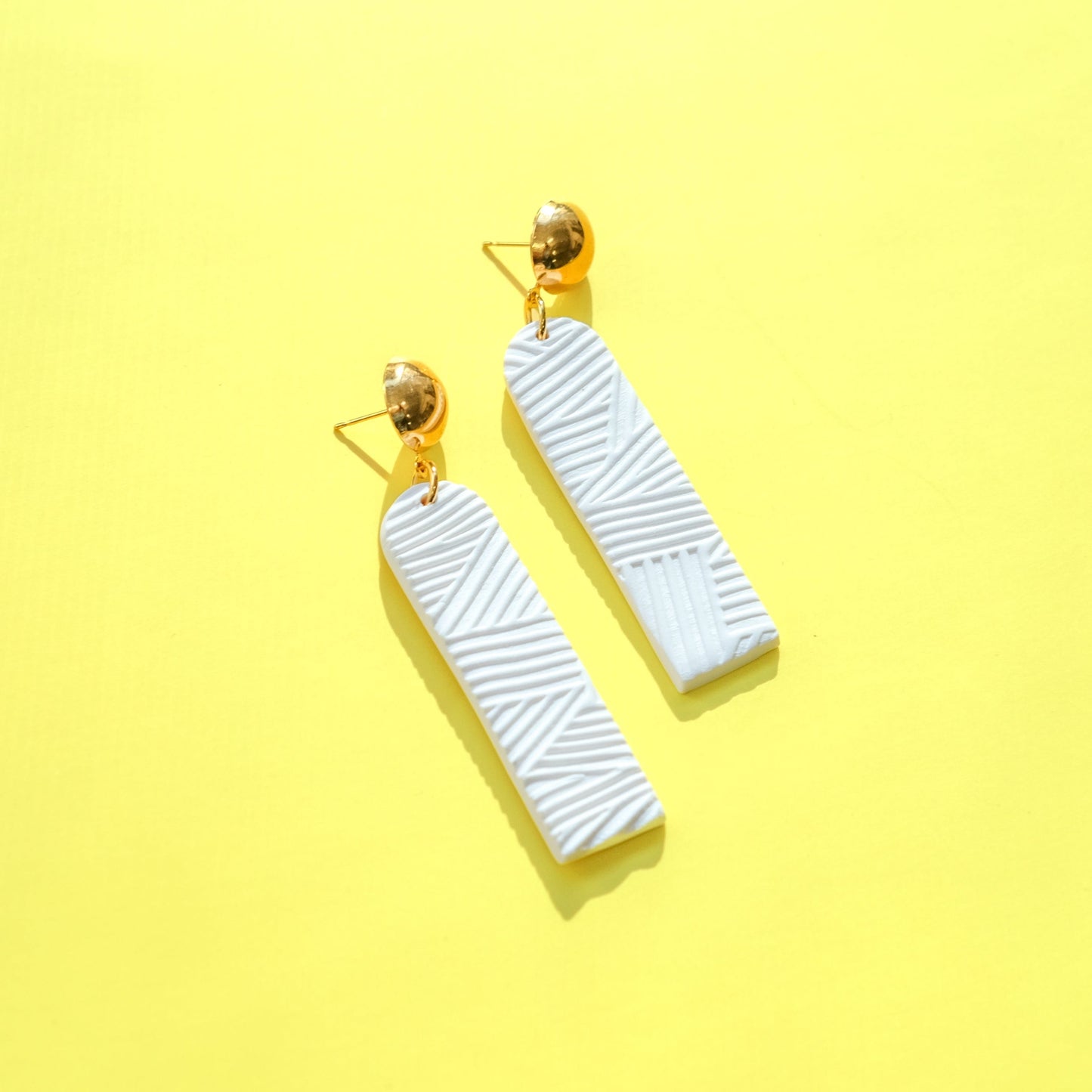 Elegant elongated Chelsea dangly earrings in textured white #color_white-textured-lines