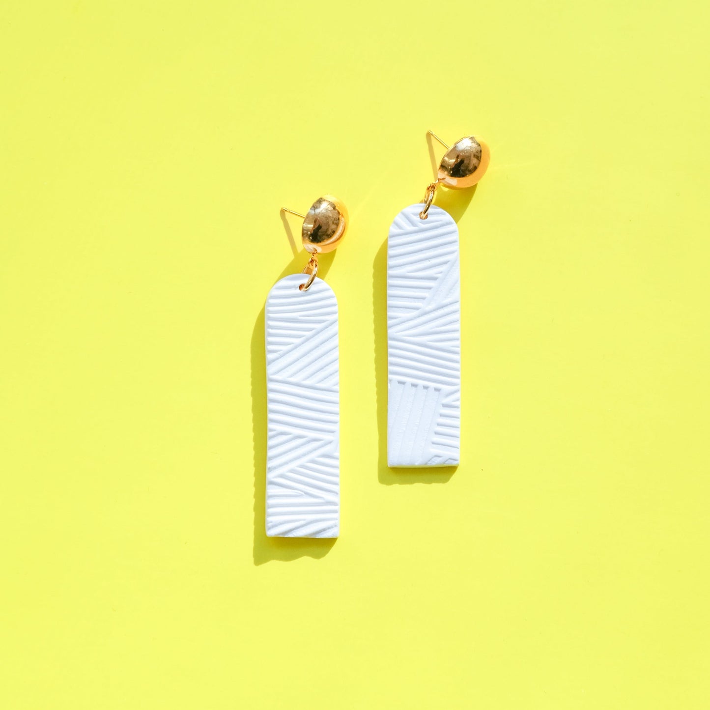 Elegant elongated Chelsea dangly earrings in textured white #color_white-textured-lines