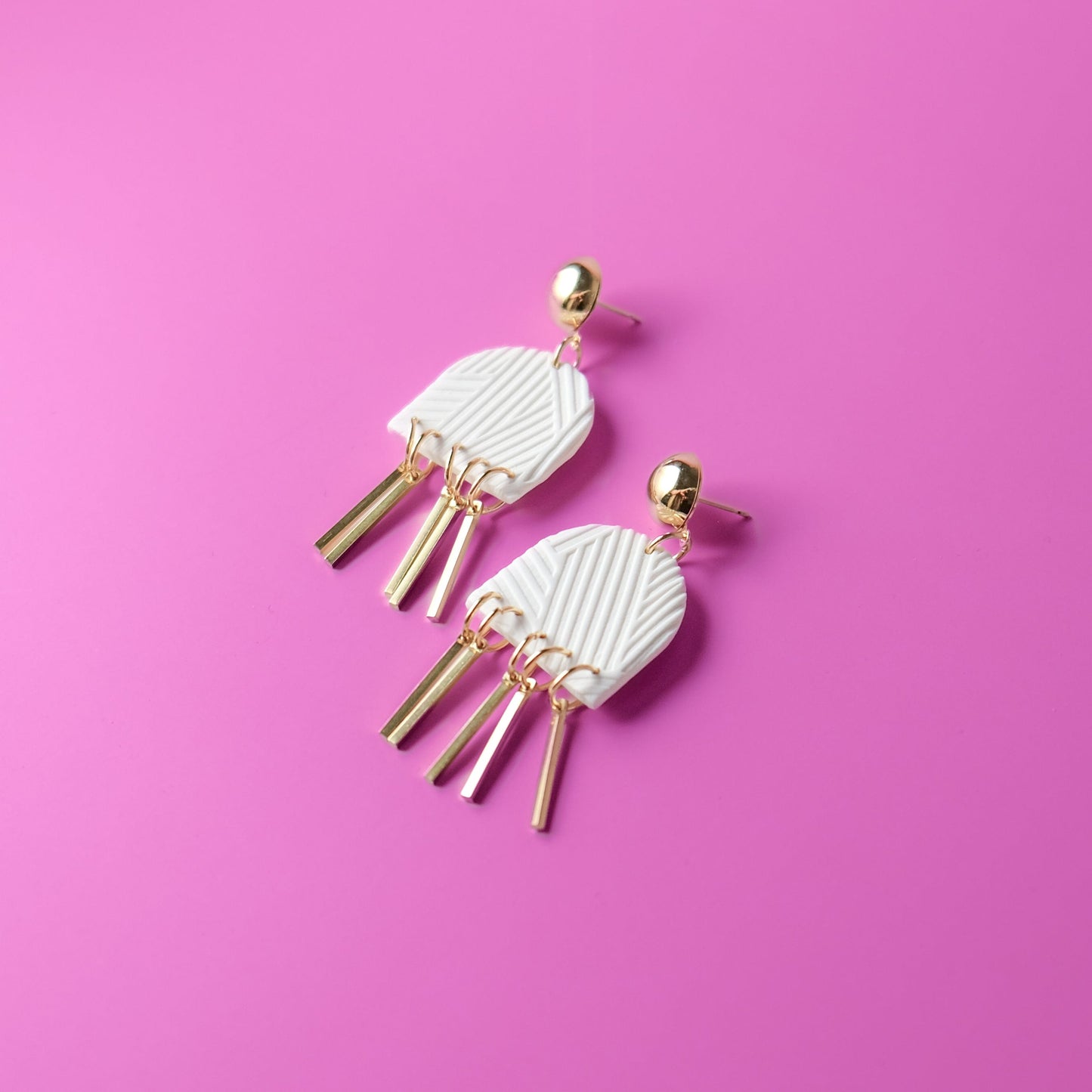 Dancing Domes dangly earrings in white and gold #color_white-textured-lines