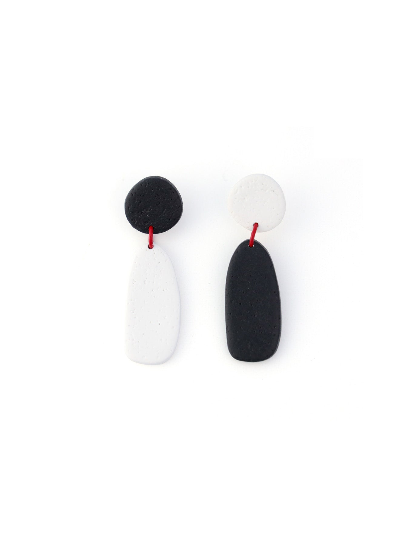 Black–white abstract earrings, sculptural, lightweight, asymmetric pebble shapes joined by red accent #color_black-white