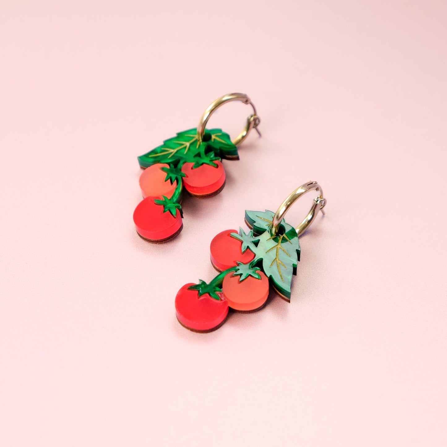 Tomato-vine dangle earrings, polished gold huggie hoops, layered acrylic charms, etched leafy details, clustered cherry shapes in vivid tomato red #color_red