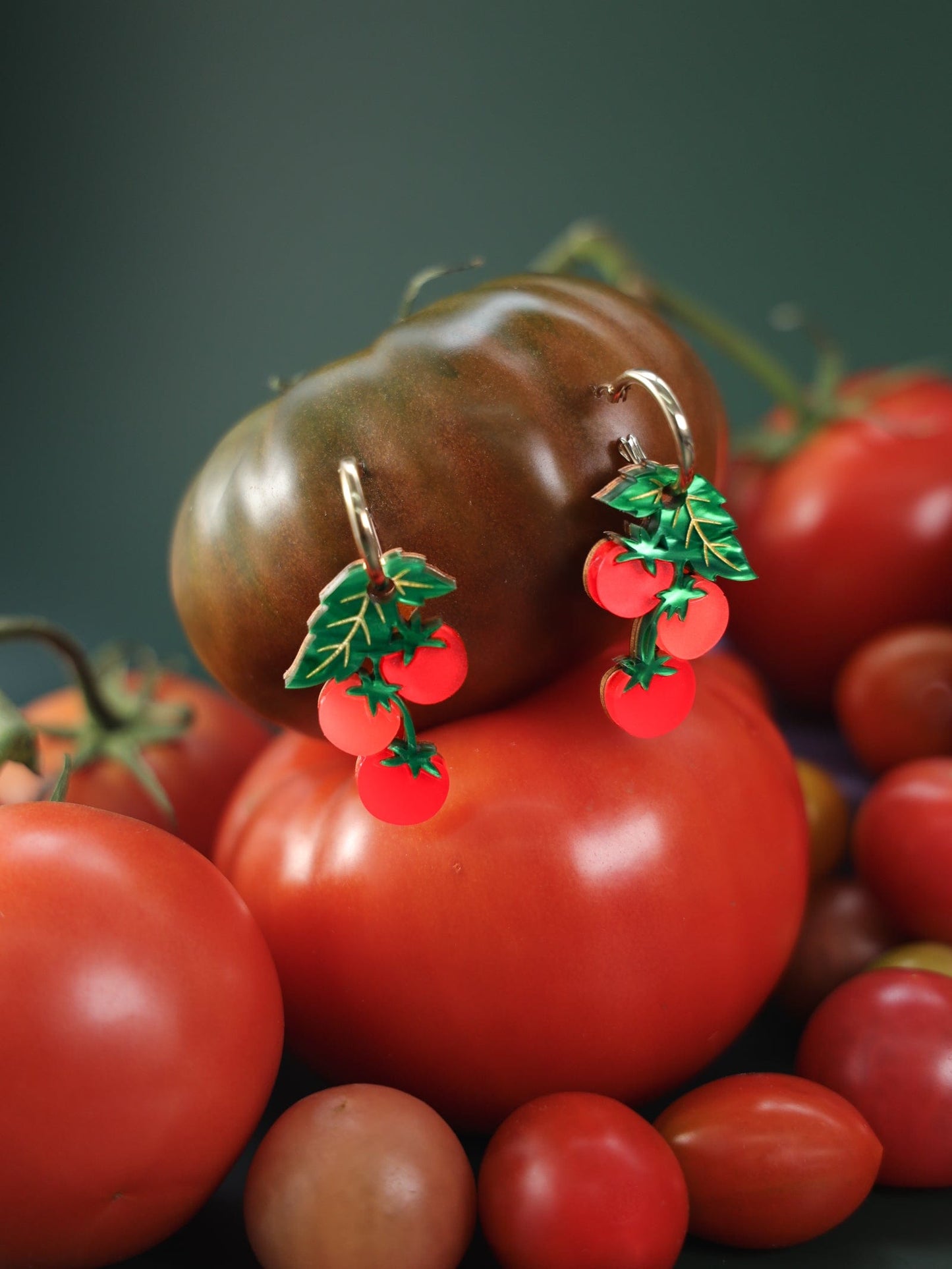 Tomato-vine dangle earrings, polished gold huggie hoops, layered acrylic charms, etched leafy details, clustered cherry shapes in vivid tomato red #color_red