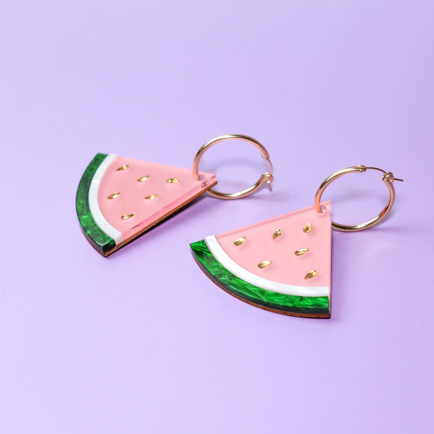 Watermelon wedge hoop charms, glossy pastel-pink flesh, marbled emerald-green rind with crisp white stripe, sprinkled with shiny gold seeds, playful summertime statement #color_pink_green