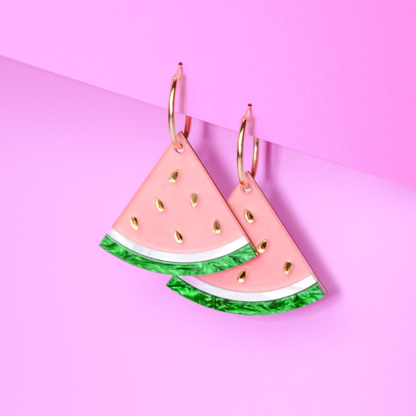 Watermelon wedge hoop charms, glossy pastel-pink flesh, marbled emerald-green rind with crisp white stripe, sprinkled with shiny gold seeds, playful summertime statement #color_pink_green