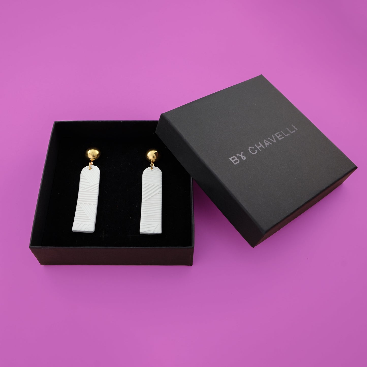 Elegant elongated Chelsea dangly earrings in textured white #color_white-textured-lines