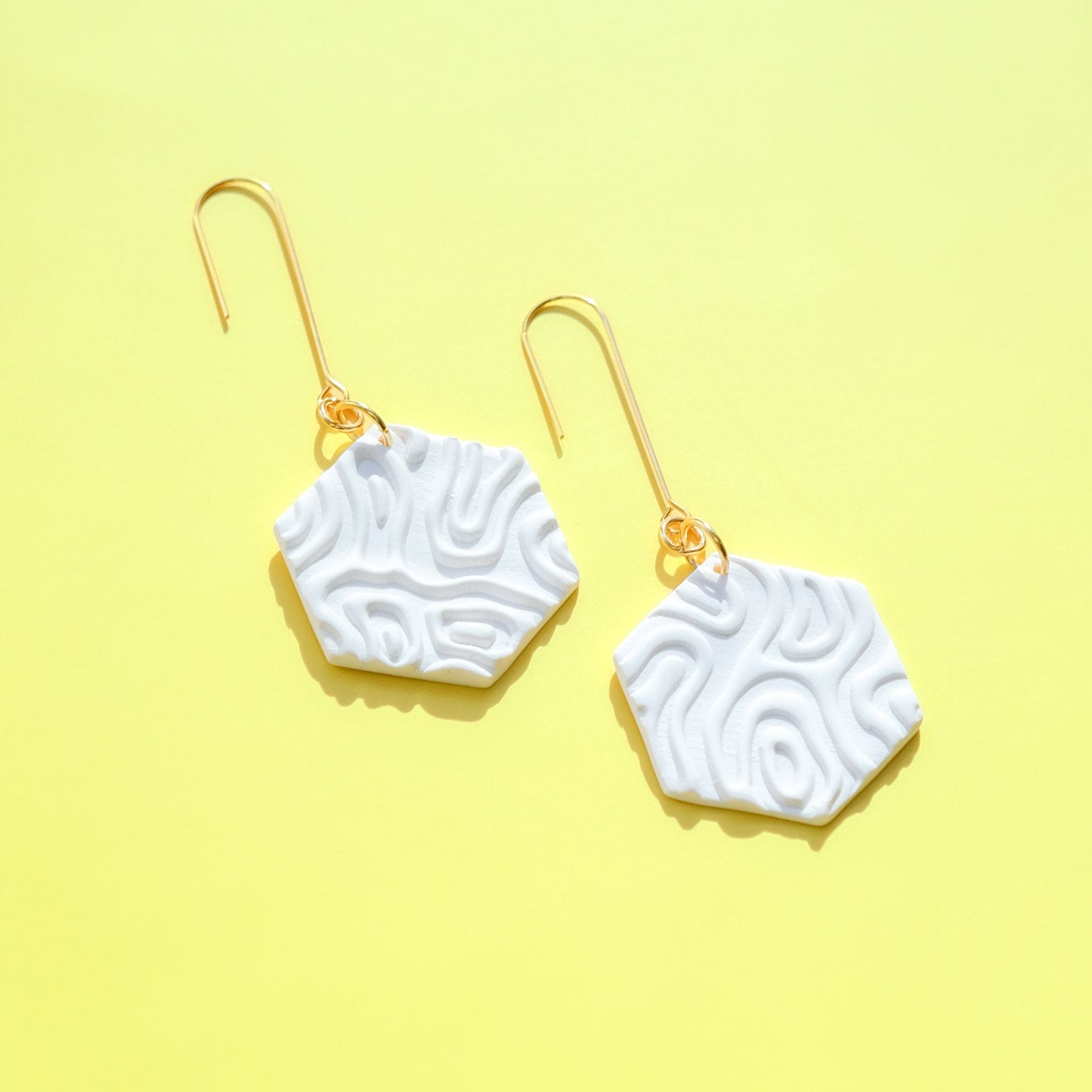 Swinging Hex Dangly Earrings #color_white-topographic-texture