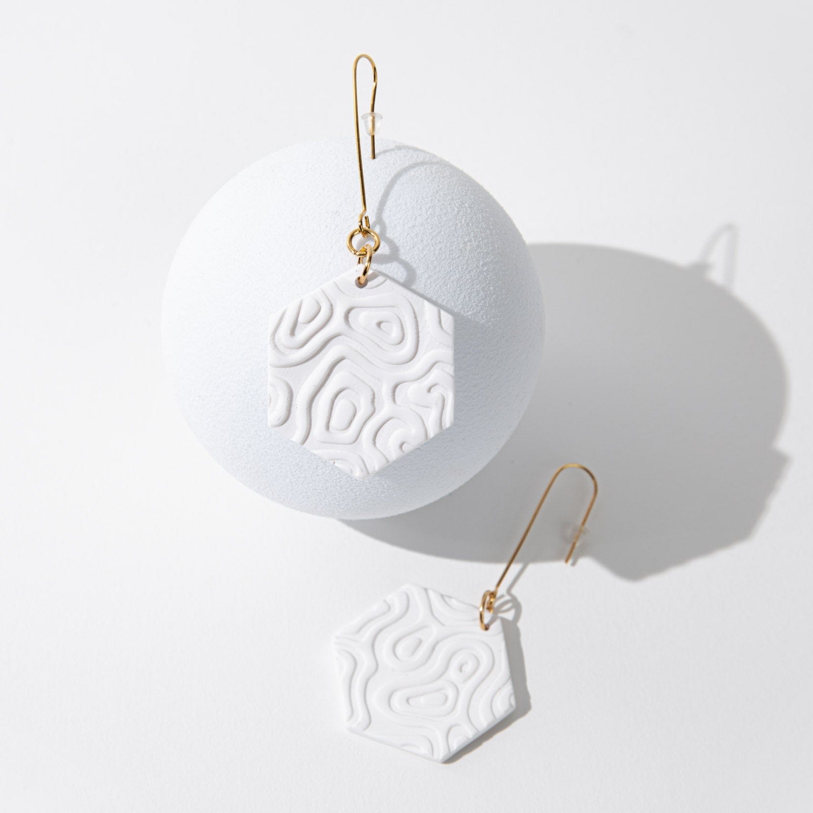 Swinging Hex Dangly Earrings #color_white-topographic-texture